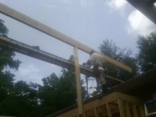 Carpenter setting a ridge beam over a new addition frame — Ice Dam Removal by Roofing Brothers in Roundup