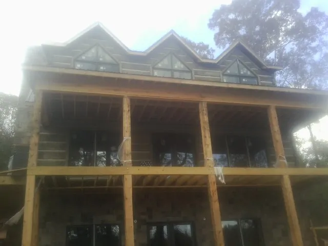 Dormers and porch framing on a large log home under construction — Roof Coating work by our crew in Roundup