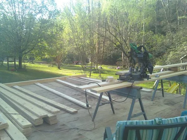 Miter saw and framing lumber on a deck under construction in Roundup
