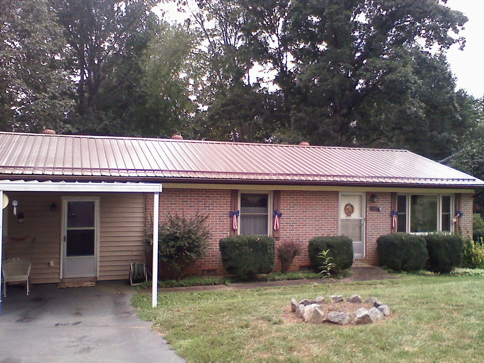 Bronze metal roof and carport on a brick ranch home — Roof Repair work by our crew in Roundup