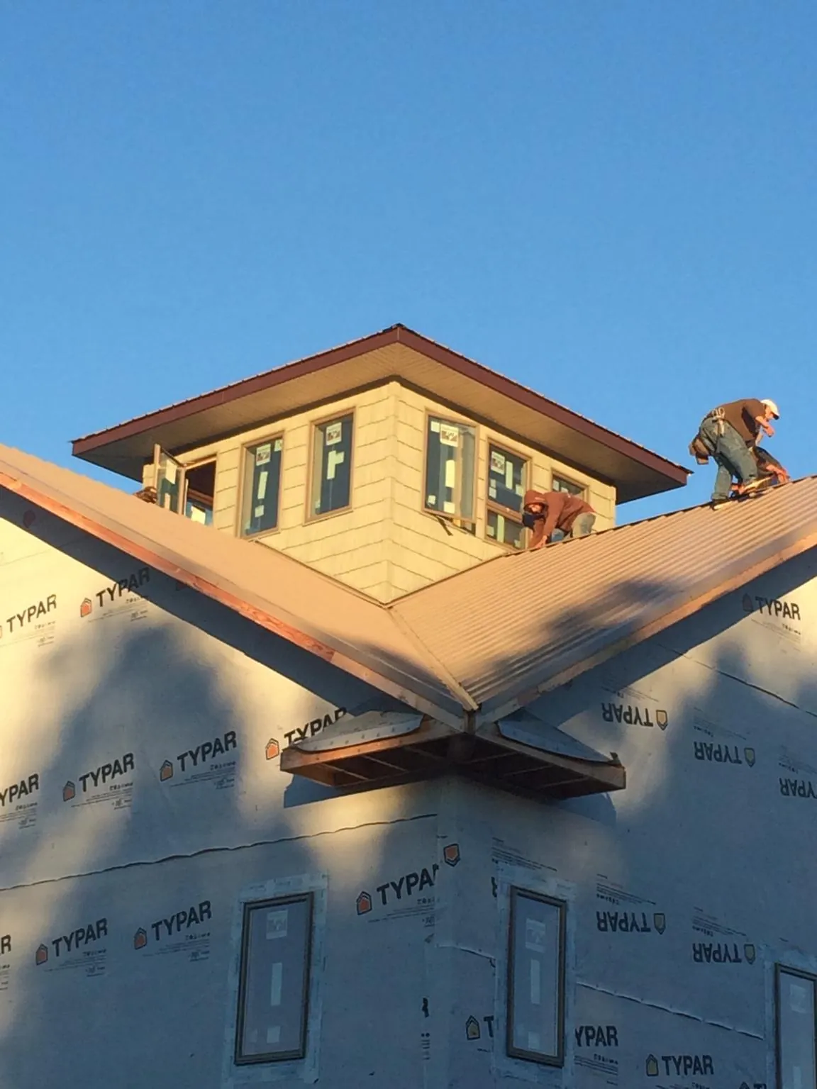 Roofers working around a rooftop cupola on a new metal roof at sunset — Roof Waterproofing in Roundup by Roofing Brothers